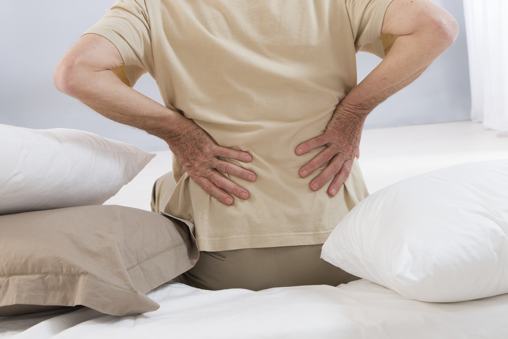 man with back pain sitting on bed