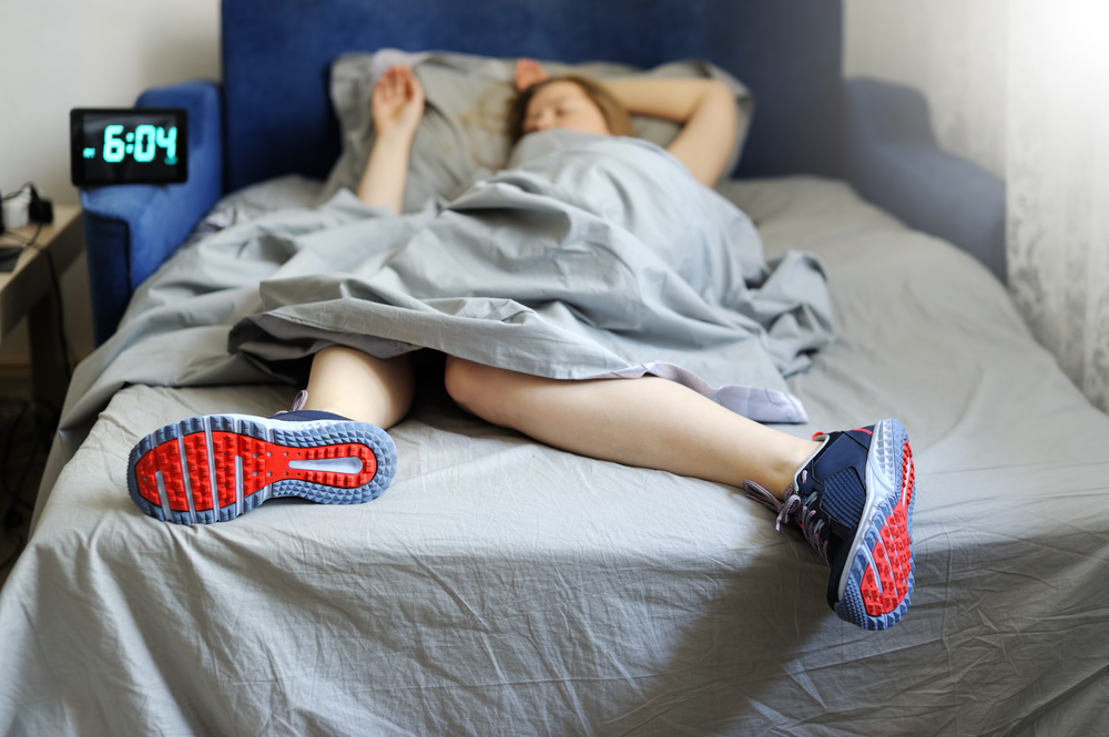 woman sleeping in bed with tennis shoes on