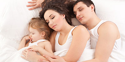 Family Sleeping On Bed